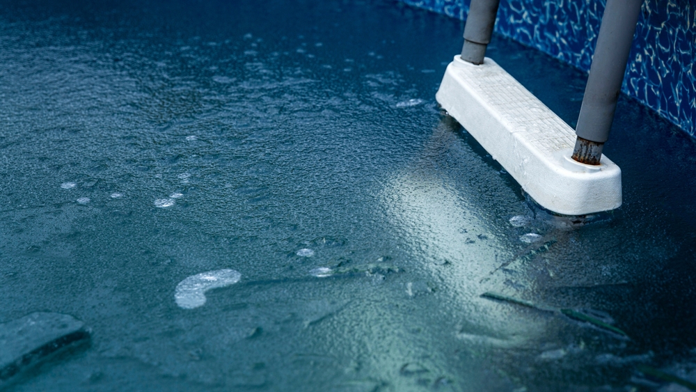 Zamarznięta powierzchnia wody i osprzętu w nieodpowiednio zabezpieczonym basenie Zamarznięta powierzchnia wody i osprzętu w nieodpowiednio zabezpieczonym basenie